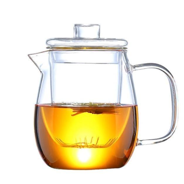 théière et tasse en verre avec fleur de thé en fleurs à l